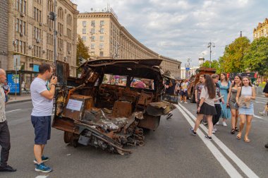 Görüntü, büyük olasılıkla Rus-Ukrayna çatışmasından kaynaklanan kentsel çevredeki hasarlı bir aracı gösteriyor. Çevredeki insanlar hayatta kalanlar, görgü tanıkları veya yerlerinden edilen siviller Kyiv, Ukrayna 08-24-2024