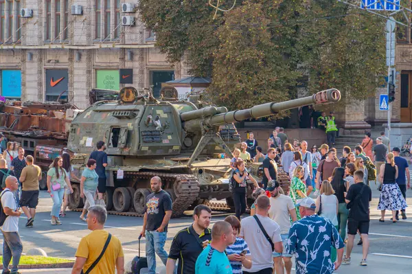 Görüntü, muhtemelen Rus-Ukrayna çatışmasıyla ilgili askeri bir gösteri veya gösteri tasvir ediyor. Ukrayna 08-24-2024 askeri teçhizatı Kyiv, Ukrayna 'yı izleyen bir D-20 havan topunu ve sivilleri içeriyor.