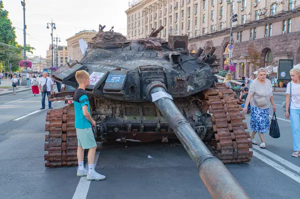 Görüntü, muhtemelen Ukrayna 'da bir şehir ortamında bir T-72B tankı gösteriyor. Çevrede siviller var. Çatışmaya girmemişler ama büyük ihtimalle mor Kyiv, Ukrayna 08-24-2024