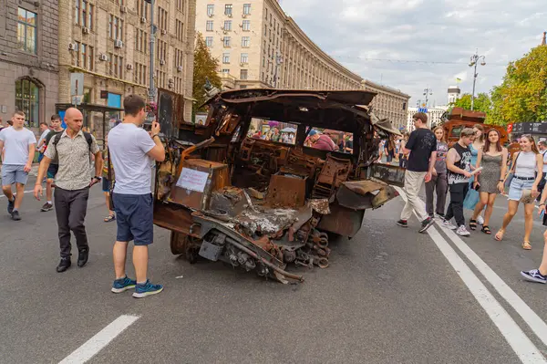 Görüntü, muhtemelen Rus-Ukrayna çatışması ile ilgili hasarlı bir askeri aracın şehir sahnesini gösteriyor. Çevre, tartışmalı bir bölge olduğunu gösteriyor. Siviller ise p Kyiv, Ukrayna 08-24-2024