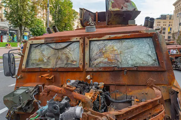 Görüntü, hasar görmüş ve paslanmış bir tankla kentsel bozulma sahnesini tasvir ediyor. Çevre alanı bitkisel hayata sahip olmayan harap binalardan oluşuyor.