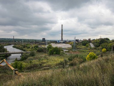 Çimenlik alanlar, ağaçlar, bir su kütlesi ve kayalar arasında yer alan sanayi fabrikası. Sahne, Kostiantynivka, Ukrayna, 06-15-2013