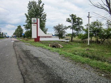 Çimenli bir bölgedeki kırmızı ve beyaz bir yapının yan görüntüsü, muhtemelen bir işaret veya anıt Arka plan, kısmen kalabalık Kostiantynivka, Ukrayna, 06-15-2013 altında dağınık ağaçlarla dolu bir açık alanı gösteriyor