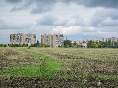 Görüntü tarla ve yerleşim alanlarının bir karışımını gösteriyor, önü ve arkasındaki apartman binaları yeni sürülmüş. Sahne Kostiantynivka, Ukrayna, 06-15-2013