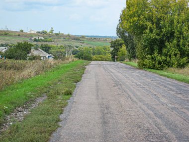 Görüntü, uzakta, açık gökyüzünün altında yemyeşil tepeleri olan iyi korunmuş bir kırsal yol gösteriyor. Hiçbir araç, insan veya hayvan yok, ilave olarak Kostiantynivka, Ukrayna, 06-15-2013
