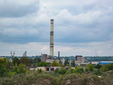 Görüntü, önde gelen tuğla baca ile çevrili terk edilmiş bir sanayi bölgesini tasvir ediyor. Üretim ve işleme için kullanılan diğer binalar da var.