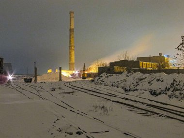 Demiryolu raylı gece karlı manzarası, yakın zamanda gerçekleşen araç hareketleri, yanan bina, endüstriyel yapılar, baca veya baca, atmosferik, muhtemelen terk edilmiş Kostiantynivka, Ukrayna, 01-15-2013