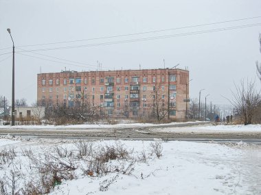Kar kaplı duvarları, görünür perdeleri, balkonları ve önünde eriyen bazı açık mobilyaları olan çok katlı bir binanın kış görüntüsü, Kostiantynivka, Ukrayna, 01-15-2013