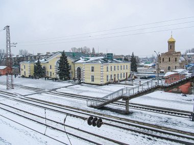 Bir demiryolu, paralel raylar, küçük bir platform ve aralarında önde gelen sarı bui Kostiantynivka, Ukrayna, 01-15-2013 'ün de yer aldığı mimari ayrıntılara sahip çok sayıda binanın yer aldığı karlı bir kış sahnesi.
