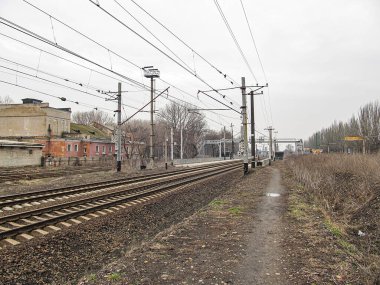 Çoklu raylı kırsal demiryolu sahnesi, bitki örtüsü, üstten kablolar, endüstriyel çevre, bulutlu gökyüzü, dar yol, tren yolu veya Kostiantynivka, Ukrayna, 01-15-2013