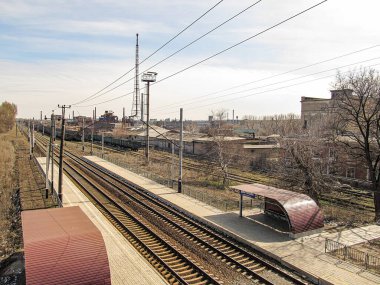 Birden fazla raylı bir şehir tren istasyonu, barınak altında oturma, sanayi veya kuru ortam, uzak binalar, parçalı bulutlu gökyüzü, c Kostiantynivka, Ukrayna, 01-15-2013