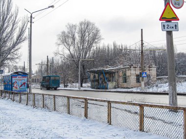 Kısmen görünür mavi bir tramvay, sokak lambası ve bir mağaza vitrininin yer aldığı bir kış manzarası. Elektrik hatları ve bir tabela da görünür Kostiantynivka, Ukrayna, 01-15-2013