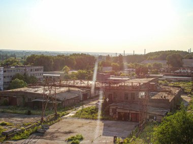 Terk edilmiş bir sanayi bölgesinin yüksek görüş açısı, sol tarafındaki eski fabrika binaları bozulma belirtileri gösteriyor ve tabiat sağ tarafı geri istiyor.