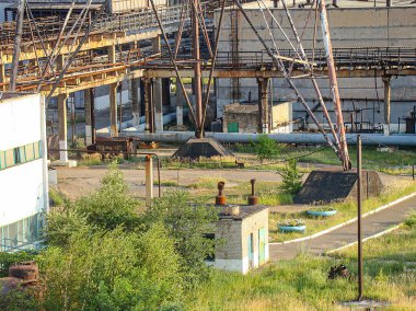 Aşırı büyümüş çimen ve molozların olduğu terk edilmiş bir sanayi bölgesi, kısmen kıvrımlı metal yapı, paslı borular, büyük beton altyapı, geçmiş hışmında Kostiantynivka, Ukrayna, 06-15-2013
