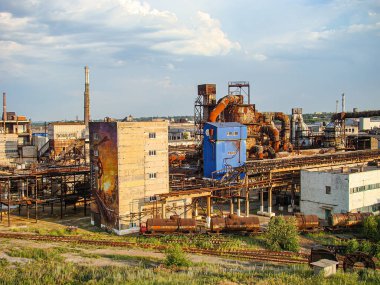 Büyük bir fabrikası, bacası ve ihmal edilmiş arka planı olan harap bir sanayi bölgesi, diğer yapıları gösteriyor, parçalı bulutlu gökyüzü, insan yok veya hareket eden Kostiantynivka, Ukrayna, 06-15-2013
