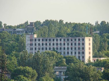 Kostiantynivka, Ukrayna 'da pencereleri, balkonları ve kısmen temiz gökyüzünü çevreleyen yeşillikleri olan çok katlı beton bir binanın havadan görünüşü, 06-15-2013