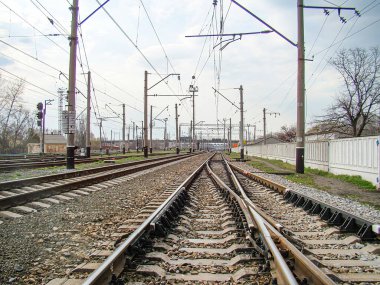 Görüntü bir demiryolu kavşağını ya da çoklu rayların birleştirildiği bir geçiş alanını resmediyor, yukarıdaki kabloların ima ettiği kapalı bir gökyüzü altında Kostiantynivka, Ukrayna, 01-15-2013