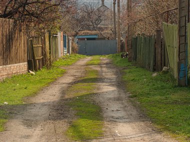 Yıpranmış ahşap çitlerle çevrili kırsal ya da banliyö çevresinden az kullanılmış toprak bir yol, sol Kostiantynivka, Ukrayna, 01-15-2013 'te mavi duvarlı bir bina kısmen görülebilir.