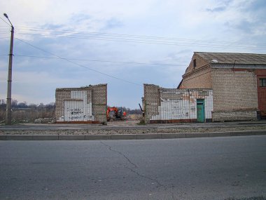 Yapı yıkım sahasının bir görüntüsü kısmen yıkılmış beton bir bina ve eski, harap olmuş bir kırmızı tuğla sokak pav Kostiantynivka, Ukrayna, 01-15-2013