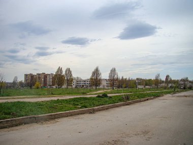 Asfaltlı bir alan, tarla, ağaçlar ve Kostiantynivka, Ukrayna, 01-15-2013 binalarıyla bulutlu bir günün samimi bir fotoğrafı.