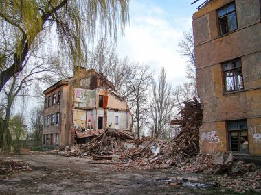 Görüntü, hasar görmüş binalar ve devrilmiş bir ağaçla bir yıkım sahnesini gösteriyor. Atmosfer kasvetli, Kostiantynivka, Ukrayna, 01-15-2013 'te çekilmiş bir felaket veya çatışma izlenimi veriyor.