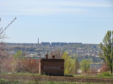 Kostiantynivka, Ukrayna 'da bir kentsel alanın ipuçlarına sahip, sonbahar ağaçları ve bulutlu gökyüzü ile çevrili, muhtemelen tarihi bir tuğla bina, 06-15-2013