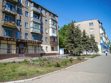 Görüntü, Orta veya Doğu Avrupa 'daki çok katlı yerleşim yerlerinin yer aldığı bir şehir sokak sahnesini gösteriyor. Kostiantynivka, Ukrayna, 06-15-2013 tarafında küçük bir bahçe, kuşlar ve park alanları bulunuyor.