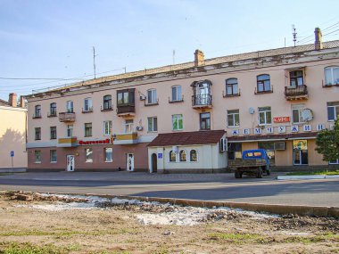 Görüntü, açık renkli bir konut binası, birden fazla balkon ve olası mağazaları olan kentsel bir sokak sahnesini gösteriyor. Bulutlu gün, Ukrayna, Kostiantynivka, Ukrayna, 06-15-2013