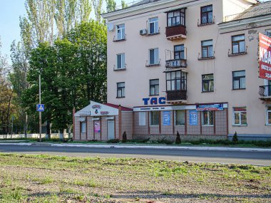 Sağ tarafta TAKS adlı küçük bir dükkanın yer aldığı sokak manzarası. Bölgede balkonlu ve ağaçlı evler var. Açık mavi gökyüzü, Kostiantynivka, Ukrayna, 06-15-2013