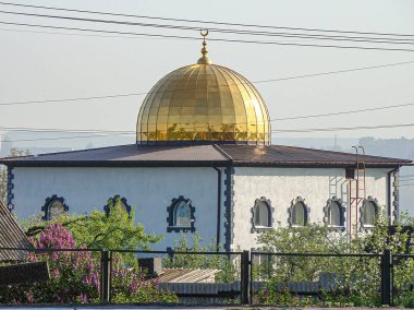Görüntü, kentsel veya banliyö ortamında bulunan altından kubbeli bir çatı ve haça sahip bir Hıristiyan kilisesi veya katedrali tasvir ediyor.