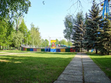 Renkli çocuk oyun parkı, taş patika, ağaçlar ve açık gökyüzü Kostiantynivka, Ukrayna, 06-15-2013