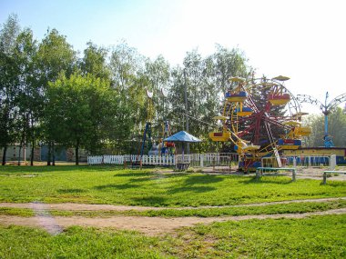 2 Temmuz 2014 'teki boş bir eğlence parkının görüntüsünde, yemyeşil ve ağaçlarla çevrili renkli bir atlıkarınca, Kostiantynivka, Ukrayna, 06-15-2013