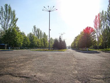 Parlak bir günde boş bir otopark, ağaçlarla çevrili beyaz çizgilerle işaretlenmiş ve muhtemelen daha büyük bir kompleks olan Kostiantynivka, Ukrayna, 06-15-2013