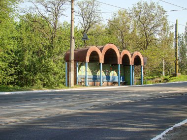 Görüntü, mavi ve sarı otobüs durağı, boş yol, ağaçlar, gökyüzü, elektrik hatları ve güneş ışığı Kostiantynivka, Ukrayna, 06-15-2013