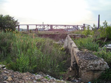 Görüntü, eski bir fabrikaya giden aşırı gelişmiş tren raylarının yer aldığı endüstriyel bir bozulma sahnesini gösteriyor. Fabrika doğayla çevrili, alanı geri istiyor, Kostiantynivka, Ukrayna, 06-15-2013