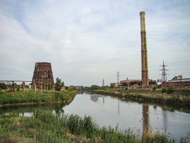 Bir tarafta sanayi bölgesinin, diğer tarafta yeşilliğin yeşerdiği bir su yolu manzarası. Sahne, doğayla Indu Kostiantynivka, Ukrayna, 06-15-2013 arasındaki zıtlığı resmediyor.