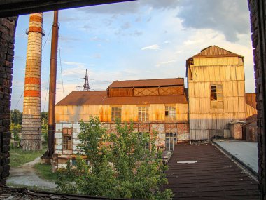 Terk edilmiş ya da harap olmuş bir sanayi fabrikası. Aşırı gelişmiş bitki örtüsü, paslı yapılar, kırık pencereler, önemli bir baca yığını, Kostiantynivka, Ukrayna, 06-15-2013