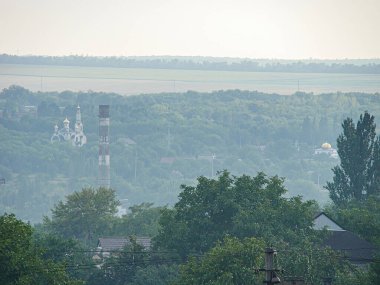Rusya 'dan etkilenen binalar, ağaçlar ve bir kule gökyüzü bulutlu bir araziye tepeden bakıyor. Muhtemelen sabah ya da öğleden sonra erken saatlerde, Kostiantynivka, Ukrayna, 06-15-2013