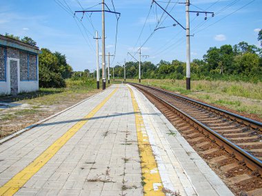 Yıpranmış bir platformu, küçük bir binası ve yemyeşil ağaçları olan kırsal bir tren istasyonu. Gündüz çekilen fotoğraflarda Kostiantynivka, Ukrayna, 06-15-2013 elektrik hatları görünmüyor.