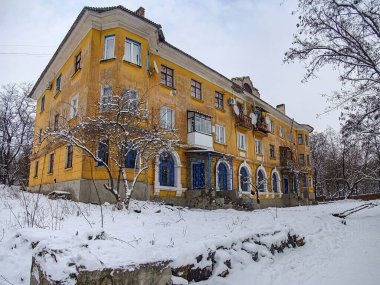 Daha soğuk iklimlere sahip bir bölgede bulunan sarı ve koyu renk şemasına sahip geleneksel çok katlı bir yerleşim yeri. Görüntü karlı metni Kostiantynivka, Ukrayna, 01-15-2013 'ü gösteriyor.