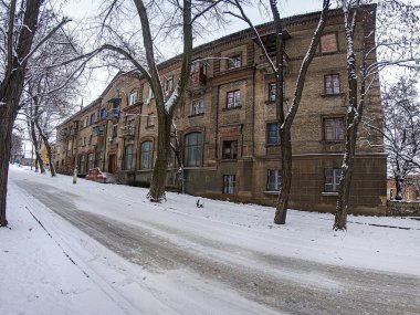 Görüntü, çok katlı binaları ve buzlu yolları olan karlı, Avrupa tarzı bir şehir caddesini gösteriyor. Ağaçların çıplak dalları var ve Kostiantynivka, Ukrayna, 01-15-2013 tarihlerinde hemen hiçbir insan veya araç görülmüyor.