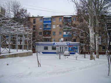 Sovyet mimarisinin tipik bir yerleşim yeri olan karlı bir şehir manzarası, yakınlardaki küçük ticari bir yapı ve taze karla kaplı zemin Kostiantynivka, Ukrayna, 01-15-2013