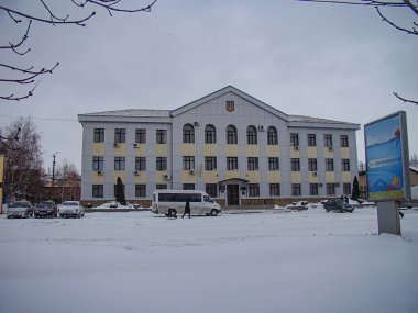 Soğuk şehir ortamında simetrik cepheli ve muhtemel balkonlu çok katlı bir bina, karlı caddede park edilmiş araçlar, gökyüzü Kostiantynivka, Ukrayna, 01-15-2013