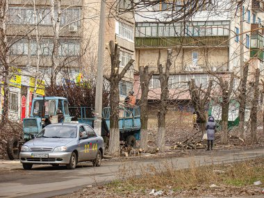 Bir şehir sokak sahnesinde mavi bir araba ve büyük bir kamyonet yer alıyor. Muhtemelen her ikisi de park halinde, kamyon platformunda ekipman ve malzemelerle birlikte. Kostiantynivka, Ukrayna, 06-15-2013