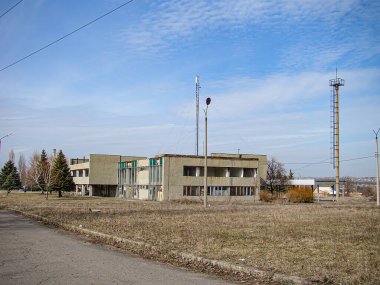 Çimenli, düz bir alanda iki katlı bir bina, markalaşma veya belirgin özellikleri yok, sol tarafta elektrik direkleri, ve arka planda Kostiantynivka, Ukrayna, 01-15-2013