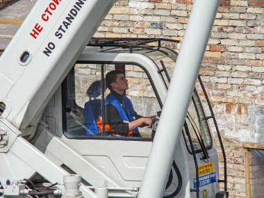 Görüntü, bir inşaat işçisinin turuncu güvenlik yeleği giydiğini gösteriyor, tehlikeli bir bölgede bir uyarı işareti ile belirtilen Kostiantynivka, Ukrayna, 01-15-2013