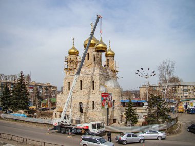 Kentsel alanda birden fazla kubbe ve minarenin yer aldığı bir cami, bir vinç, inşaat bariyeri, ağaçlar ve Kostiantynivka, Ukrayna, 01-15-2013