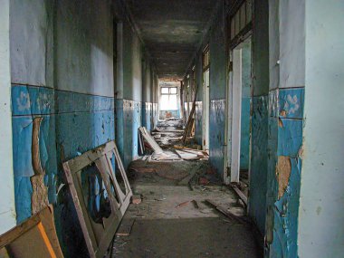 Görüntü mavi fayanslı duvarları olan hasarlı bir iç mekan, yerdeki döküntüler ve yakınlardaki bir kapıda yapısal bozulma belirtilerini gösteriyor. Işık bastırılmış, addin Kostiantynivka, Ukrayna, 01-15-2013