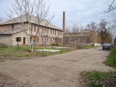 Yıkık dökük, muhtemelen terk edilmiş bir bina. Önünde asfaltsız alan, bulutlu gökyüzü ve arka planda kalan diğer binalar. Kostiantynivka, Ukrayna, 01-15-2013