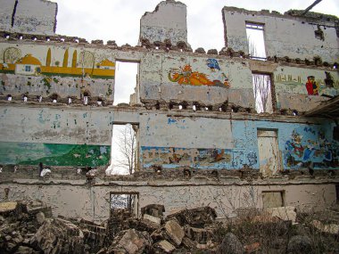 Çürüyen duvarları, rengi solmuş resimleri ve hasarlı çatısı olan bir bina. Etrafı enkazlarla dolu. Fotoğrafta eski bir Kostiantynivka, Ukrayna, 01-15-2013